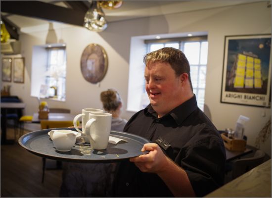 Man with learning disability serving customers in cafe